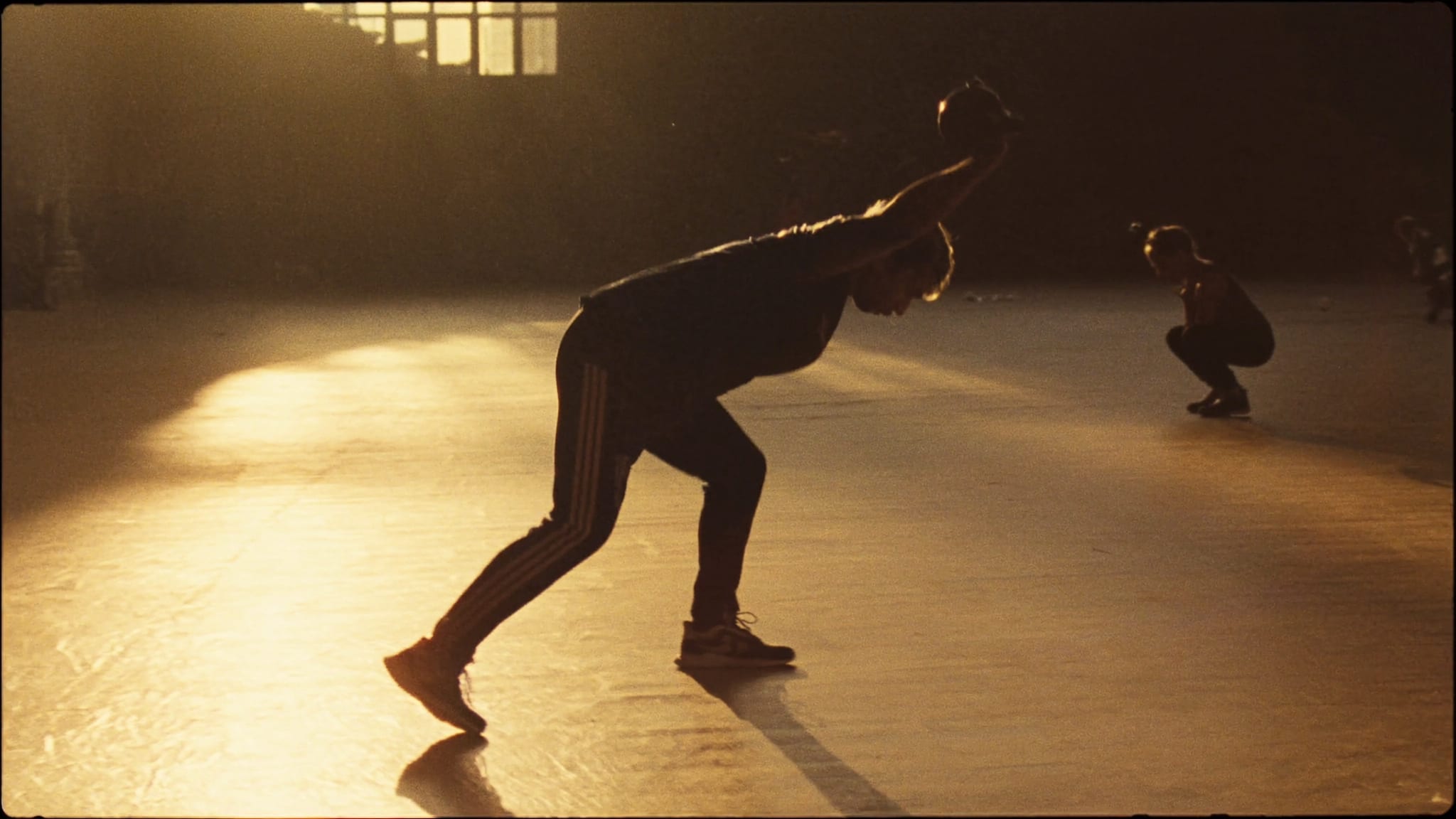 Studio al tramonto: una persona nello slancio con il kettlebell, un’altra in accosciata piu’ indietro.