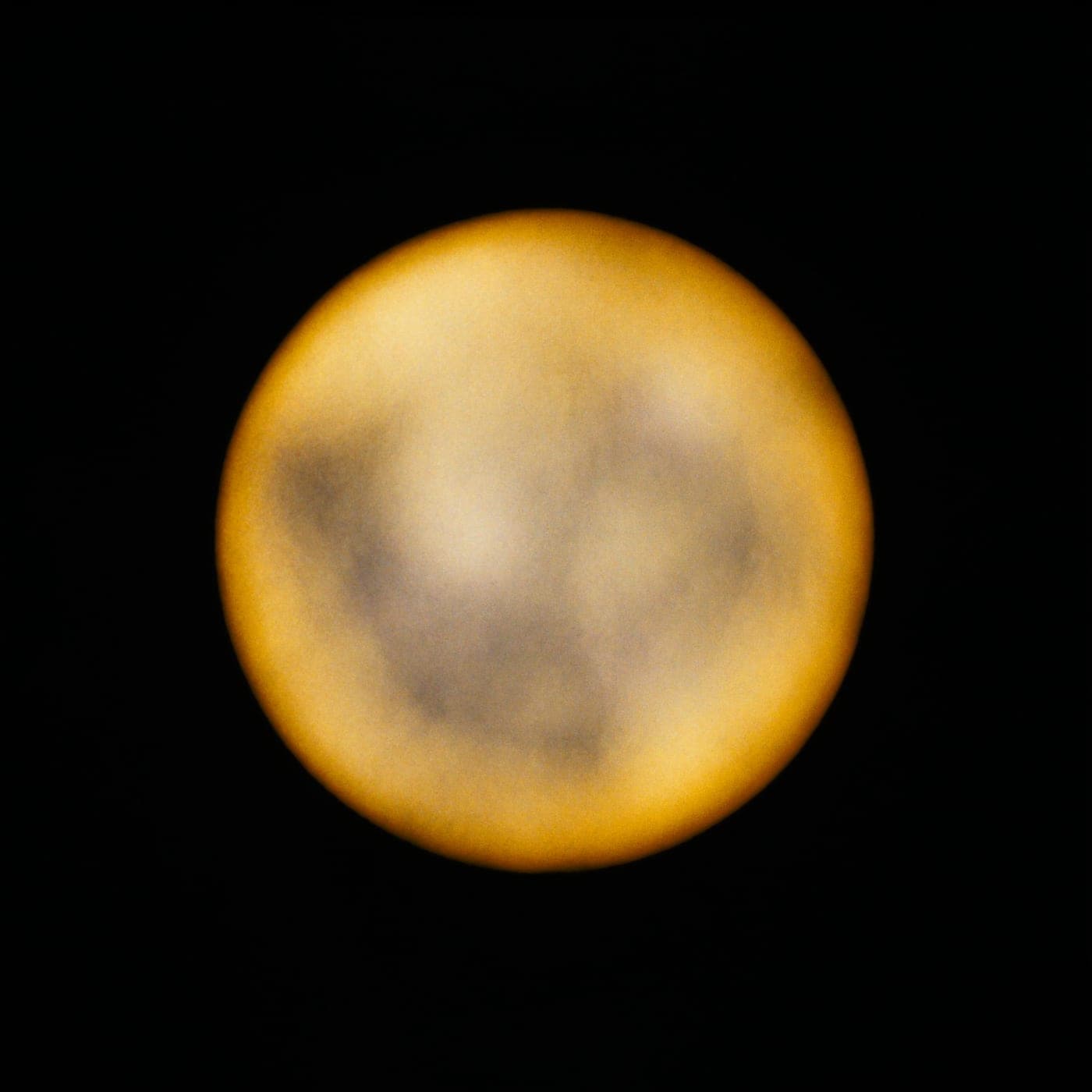Una sfera di luce calda che si deforma lentamente nel buio.