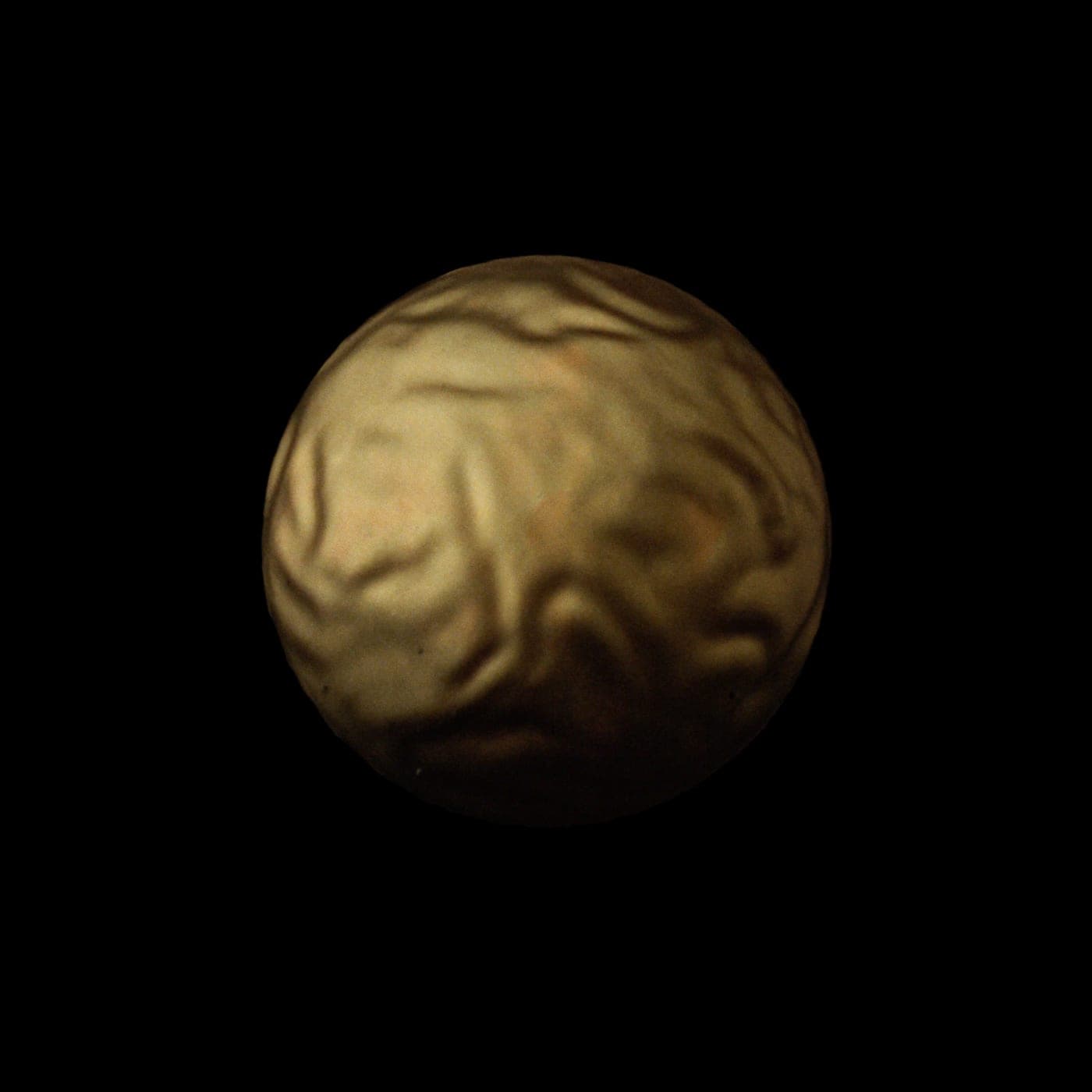 Una sfera di ottone fuso, la luce calda che scorre sulla superficie.