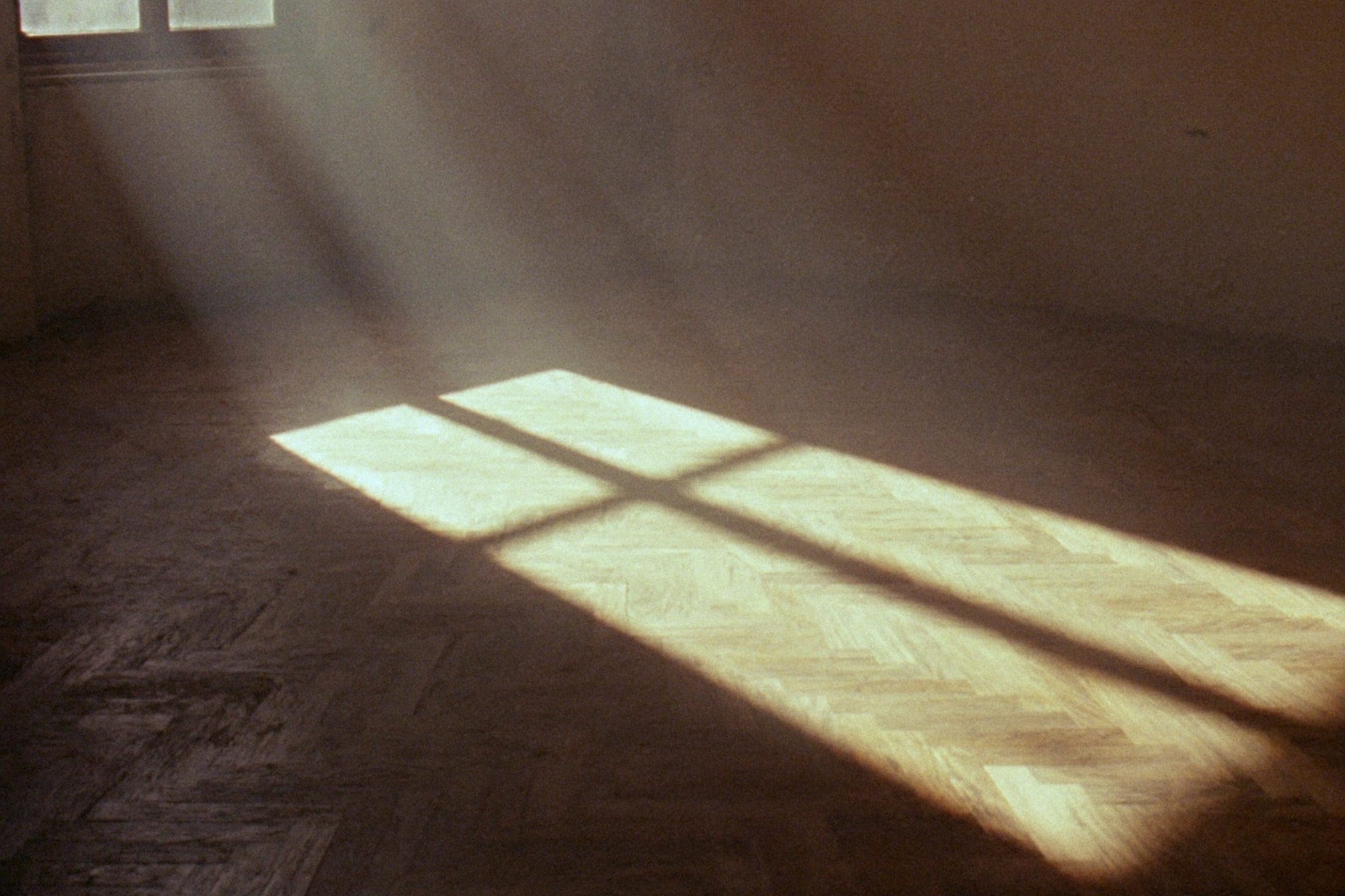 La luce della finestra disegnata sul parquet a spina di pesce di una stanza vuota, la croce del telaio proiettata sulle tavole.